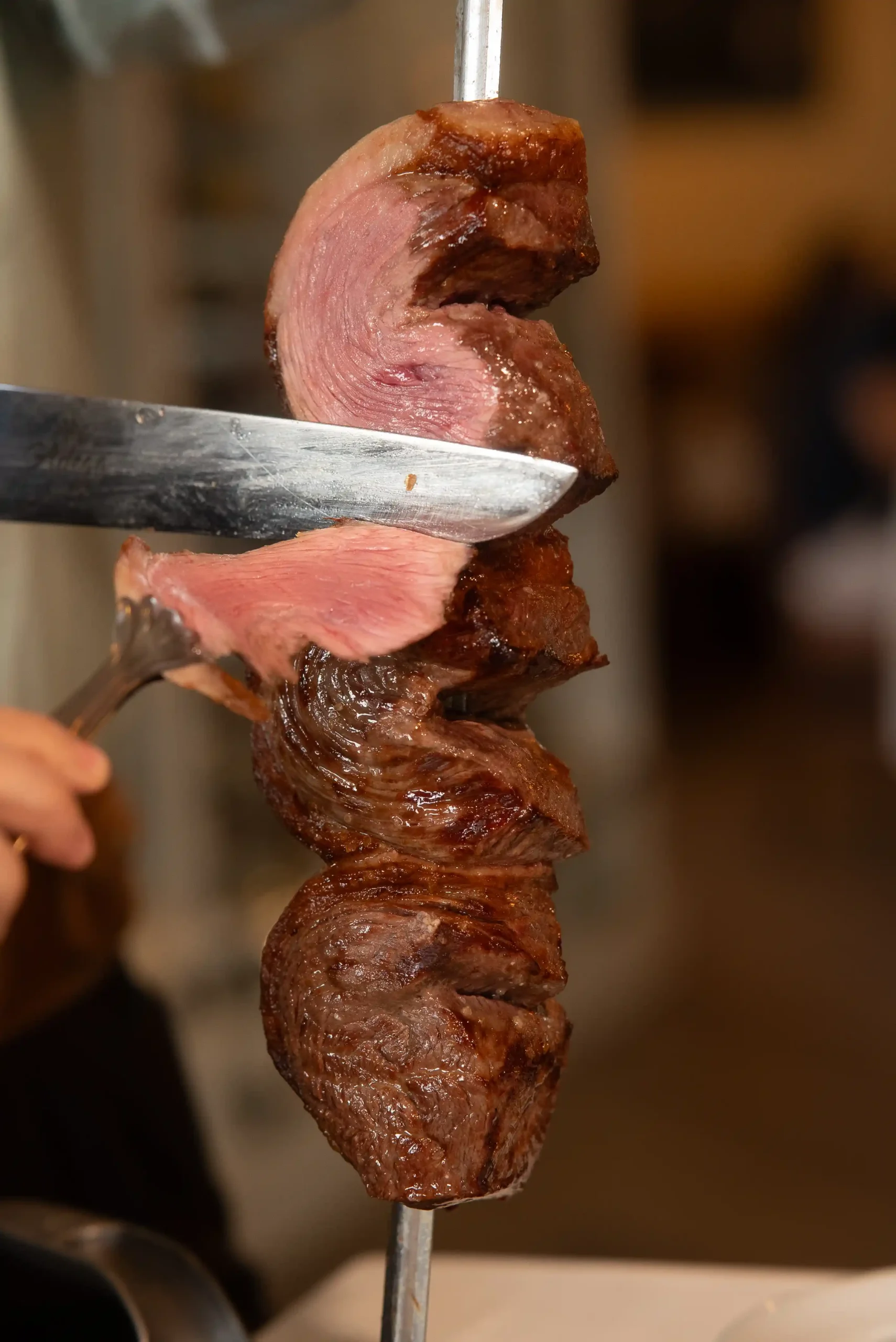 A cut of beef being sliced from the skewer at the table during brunch